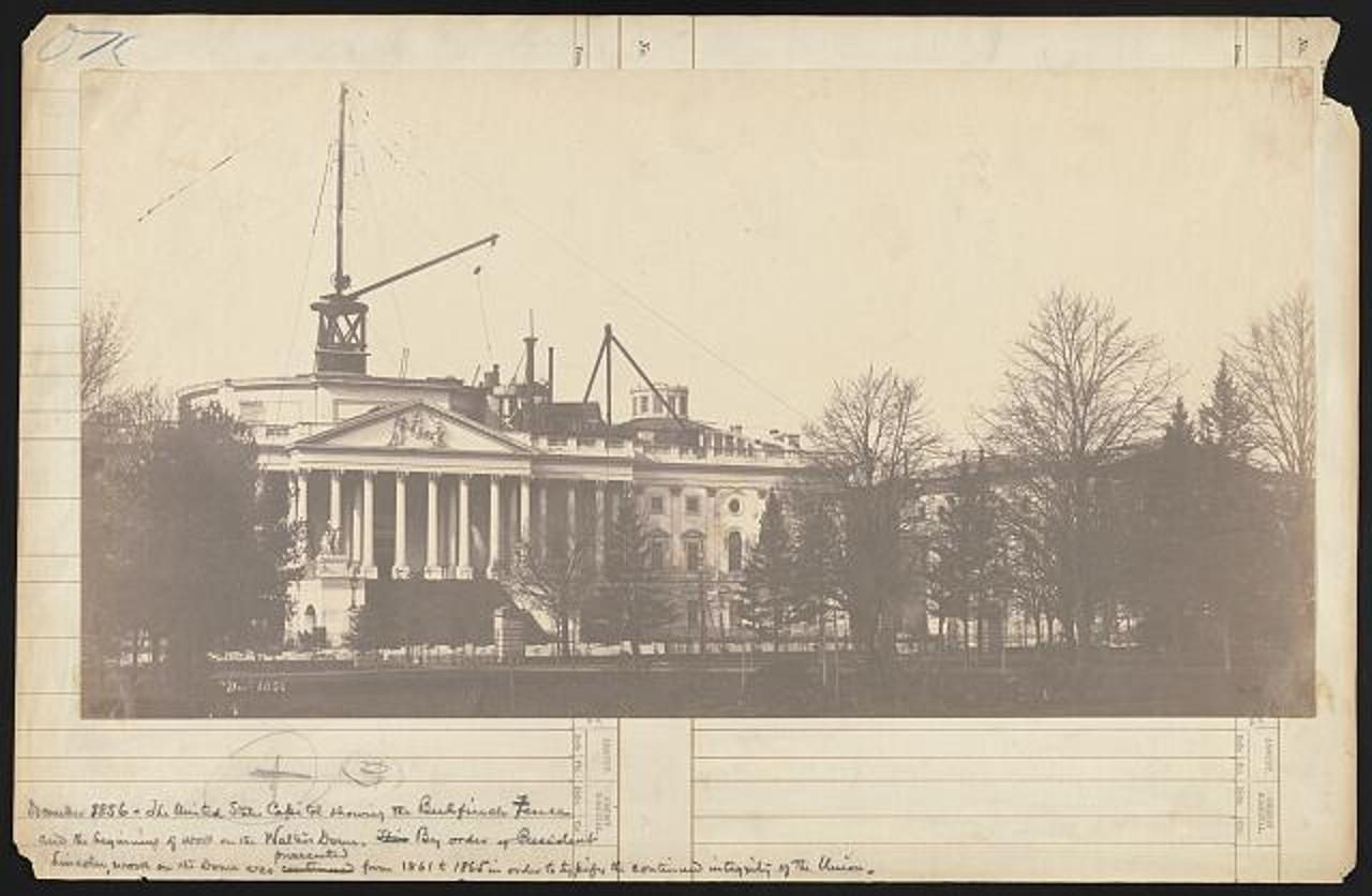 United States Capitol — the Walter dome rising, c. 1861. Unidentified photographer. Period print of the dome under construction.. Street photograph.